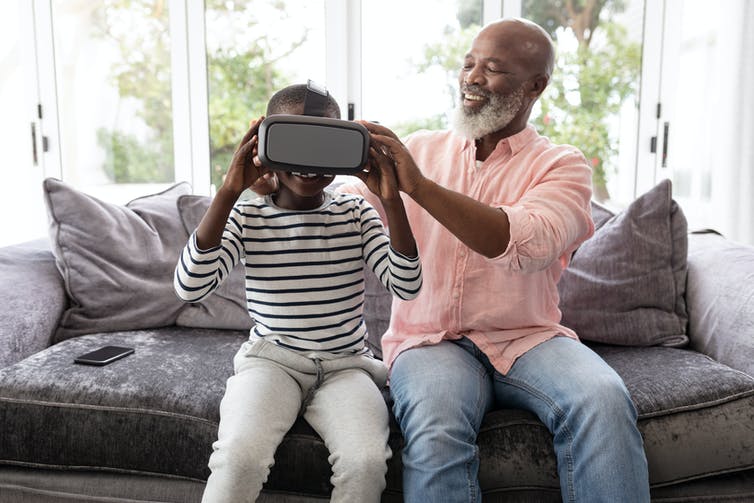 A man assists a child to put on a VR headset.
