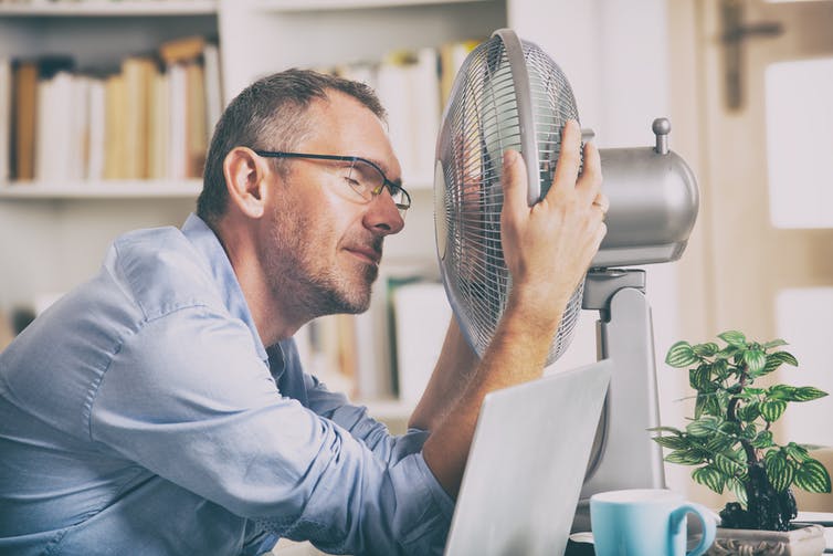 Man holds air fan close to his head