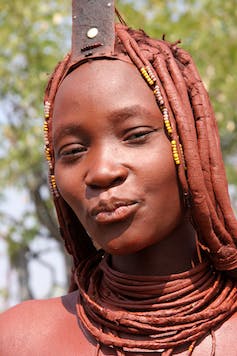 Image of a Himba woman northern cosmetically adorned with red ochre.